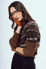 Sweater de punto color marrón, con cuello alto y diseño tejido con patrones geométricos en tonos negros y blancos en la parte superior y mangas.