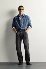 Jeans straight fit de corte recto y tiro medio, confeccionados en denim de algodón rígido con efecto lavado en color negro, de la colección especial Aaron Levine x Zara. Presentan diseño clásico de cinco bolsillos y cierre frontal con botonadura.