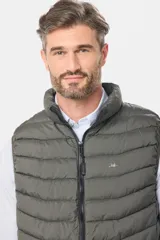 Chaleco capitoneado de color verde militar, con cierre frontal y capucha desmontable. Presenta un diseño acolchado con costuras horizontales y logo bordado en el pecho.