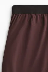 Short deportivo de doble capa en tejido funcional con tecnología DryMove para absorción de sudor. Presenta corte estándar, cintura elástica con cordón ajustable, bolsillos laterales y aberturas en el bajo. Incluye una capa interior tipo biker con bolsillo y bucle trasero para accesorios.