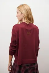 Buzo de punto color beige, con cuello redondo y manga larga.