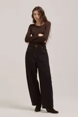 Pantalón de jean de corte wide leg en color negro, con costuras en contraste color ocre, tiro alto y cierre frontal con botón metálico.