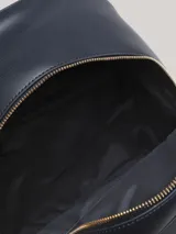 Mochila Tommy Hilfiger de diseño minimalista, confeccionada en poliuretano color azul marino. Presenta un logo monograma TH metalizado en la parte frontal, asa superior y cierre con cremallera.