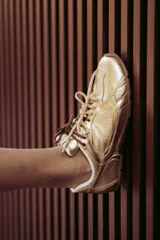 Zapatillas urbanas de cuero color tostado, con cordones verdes y suela de goma.