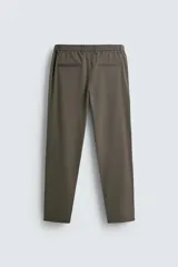 Pantalón de corte slim fit confeccionado en tejido elástico, con cintura elástica, cierre frontal con cremallera y botón, bolsillos laterales y bolsillos traseros de vivo.
