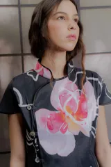 Top de tafeta verde con estampado floral en tonos azules y bordó, cuello mao, mangas cortas y cierre lateral cruzado con botones.