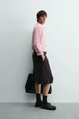 Polo de punto ligero color rosado, con cuello solapa, abertura frontal en V y manga larga.