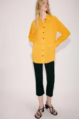 Camisa de viscosa color naranja de la colección ZW Collection de Zara, con cuello solapa, manga larga con puño, bajo asimétrico y cierre frontal con botones a contraste.