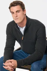 Buzo tejido de punto con textura, color gris oscuro, con cuello alto y cierre frontal parcial. Presenta puños y ruedo acanalados.