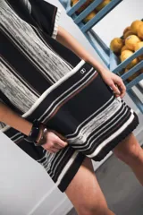 Vestido corto tejido a rayas horizontales en tonos beige y blanco, con cuello redondo y mangas cortas.