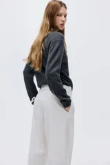 Pantalón sastrero de tiro alto con pinzas, corte holgado y piernas rectas. Presenta cierre frontal con botón y corchete ocultos, bolsillos laterales discretos y bolsillos traseros decorativos.