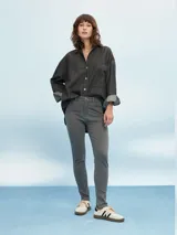 Camisa de denim azul de corte oversize, con mangas largas, cuello clásico, un bolsillo aplicado en el pecho y cierre frontal con botones metálicos.