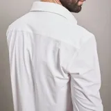 Camisa de vestir negra de manga larga, confeccionada en tejido técnico elástico y libre de arrugas, con cuello clásico y cierre frontal de botones.