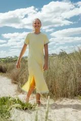 Vestido midi amarillo con cuello y mangas con terminación en celeste. Posee aberturas laterales.