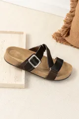 Sandalias bajas de cuero color beige con doble tira de cuero negro con textura y hebilla metálica.