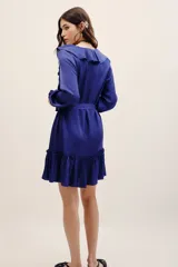 Vestido corto azul de viscosa con cuello en V, volados en el escote, mangas largas con puños fruncidos y falda con volado en el ruedo. Incluye un lazo para ajustar en la cintura.