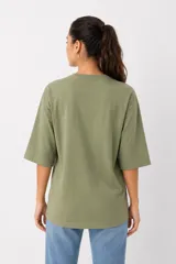 Remera de algodón color verde oliva con mangas 3/4 y cuello redondo. Presenta un diseño estampado frontal con detalles de strass y bordados.