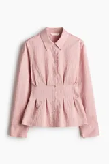Camisa entallada de mezcla de viscosa en color rosado, con efecto arrugado y bajo levemente acampanado. Presenta cuello camisero, cierre frontal de botones, canesú en la espalda y pliegues en la cintura que definen la silueta. Cuenta con mangas largas y puños abotonados.