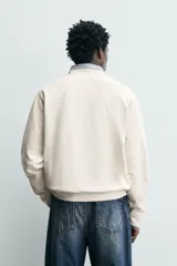 Sudadera de corte regular fit confeccionada en tejido de algodón con interior afelpado. Presenta cuello redondo, manga larga, acabados en rib y estampado de texto a contraste en el frente.