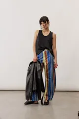 Pantalón de corte ancho y relajado con rayas verticales multicolor en tonos azul, marrón, amarillo, blanco y negro.