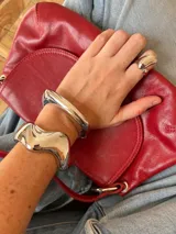 Brazalete rígido de diseño orgánico y superficie pulida con acabado plateado.