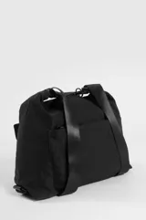 Mochila hobo color marrón claro, convertible en cartera de hombro, confeccionada en nylon. Cuenta con un compartimento principal con cierre, un bolsillo frontal con solapa y cierre de botón a presión, tiras regulables negras y un llavero colgante decorativo con cuentas coloridas y borla.