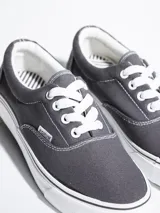 Championes de lona color azul grisáceo, estilo skate o casual, con cordones blancos y suela de goma blanca con una línea fina azul en el borde.