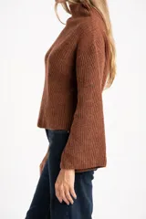 Polera de lana color marrón, con cuello alto, diseño acanalado y corte oversize con mangas anchas.