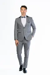 Traje formal de dos piezas compuesto por saco y pantalón de vestir. El saco presenta cierre de dos botones, solapas con detalle en contraste y bolsillos con solapa. El pantalón es de corte recto y tiro medio.