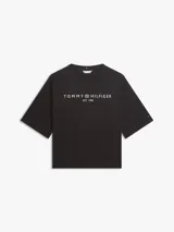 Remera negra de corte amplio de la marca Tommy Hilfiger, confeccionada en punto de puro algodón. Presenta cuello redondo, mangas cortas y anchas con hombros ligeramente caídos, y el logo de la marca estampado en el pecho en color blanco.