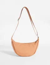 Bandolera de diseño semicircular en color camel, confeccionada en nylon. Cuenta con cierre superior y correa ajustable para llevar al hombro o cruzada.