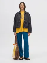 Campera de denim color negro con diseño de flecos en la parte frontal, cuello camisero y cierre frontal con botones metálicos.