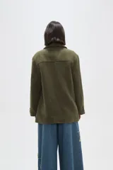 Chaqueta de corte holgado en color negro, con cuello solapa, cierre frontal con botones y bolsillos laterales.