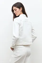Chaqueta clásica de jean color crudo, con cierre frontal de botones metálicos, bolsillos con solapa en el pecho y cuello camisero.