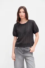 Blusa negra de broderie con mangas cortas abullonadas, cuello redondo y calce clásico.