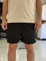 Short de baño gris liso, con diseño clásico y un pequeño parche circular con logo en la parte inferior de la pierna izquierda.