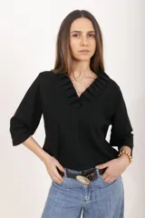 Blusa negra de lino y viscosa, con escote en V rodeado de volados plisados y mangas tres cuartos.