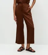 Pantalón tipo pantacourt de tiro alto, confeccionado en liocel color marrón. Presenta cierre frontal con botones forrados y elástico en la parte posterior de la cintura.