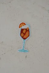 Parche decorativo termoadhesivo con el diseño de una copa de Aperol Spritz con una rodaja de naranja.