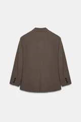 Blazer oversize de Zara con diseño a rayas verticales, cuello con solapa de muesca y hombreras. Presenta un cierre frontal cruzado con doble botonadura, bolsillos delanteros con solapa y un bolsillo de vivo en el pecho. Incluye forro interior a tono.