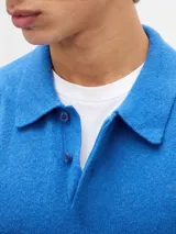 Buzo tipo polo de tejido suave, con cuello clásico, cierre frontal de botones y puños y ruedo acanalados.