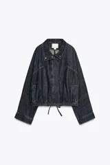 Cazadora de denim color azul oscuro, con cuello solapa, mangas largas tipo murciélago y bolsillos de vivo en el delantero. Presenta un bajo elástico ajustable con cordones y cierre frontal con cremallera y botones a presión ocultos.