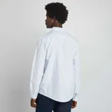 Camisa celeste de corte clásico, con cuello abotonado y mangas largas con puños abotonados.