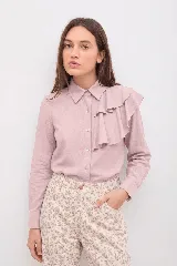 Camisa de lino color rosado, con cuello clásico, cierre frontal de botones y detalle de volados en el hombro izquierdo.