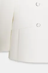 Blazer blanco de manga larga con cuello solapa y hombreras. Diseño cruzado con cierre frontal de cuatro botones y bolsillos delanteros con solapa.