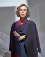 Tapado largo de lana merino afieltrada color rojo y violeta con diseño degradado. Tiene bolsillos laterales y puede usarse suelto o cruzado.