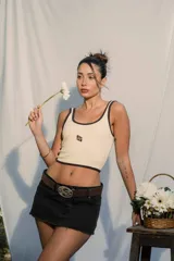 Top sin mangas color marrón oscuro con ribetes color beige, corte crop y logo bordado en el centro del pecho.