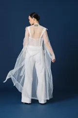 Trench largo de mujer confeccionado en tul transparente, con cuello camisero, mangas largas y frente abierto. Presenta una caída fluida y ligera, ideal para superponer sobre otras prendas.