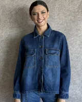 Sobrecamisa de denim azul con cuello camisero, cierre frontal con botones, mangas largas con puños abotonados y dos bolsillos con solapa en el pecho.
