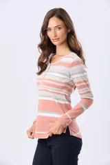 Remera de algodón de manga larga, con cuello redondo y botones en la parte superior. Presenta un estampado de rayas horizontales en tonos coral, beige, blanco y verde menta.